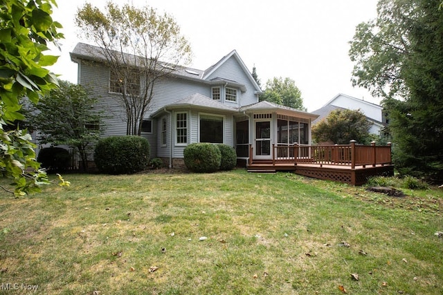 back of property with a sunroom, a deck, and a lawn