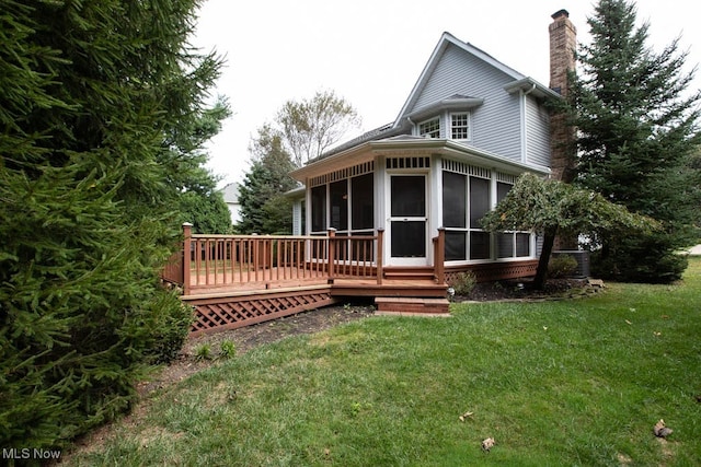 back of property featuring a yard, a sunroom, and a deck