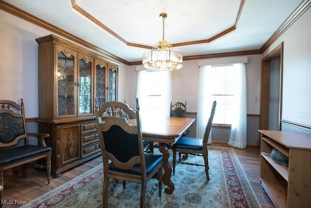 dining area with ornamental molding, a notable chandelier, and dark wood-type flooring