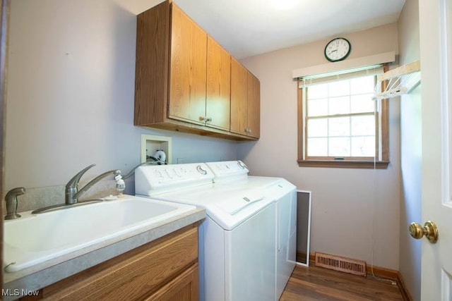 laundry area featuring separate washer and dryer, cabinets, sink, and dark wood-type flooring