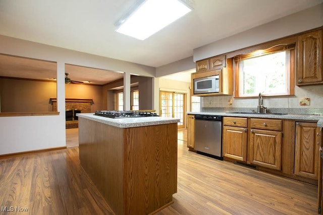 kitchen with a center island, tasteful backsplash, sink, light hardwood / wood-style floors, and appliances with stainless steel finishes