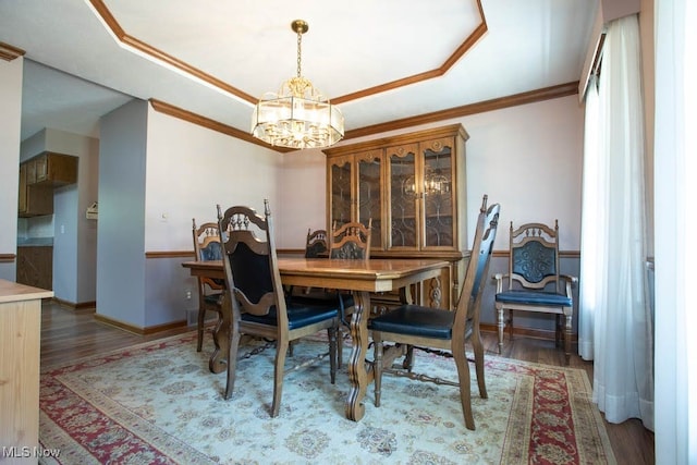 dining space with a notable chandelier, a tray ceiling, crown molding, and dark wood-type flooring