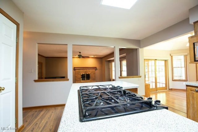 kitchen with ceiling fan, black gas cooktop, dark hardwood / wood-style floors, and light stone counters