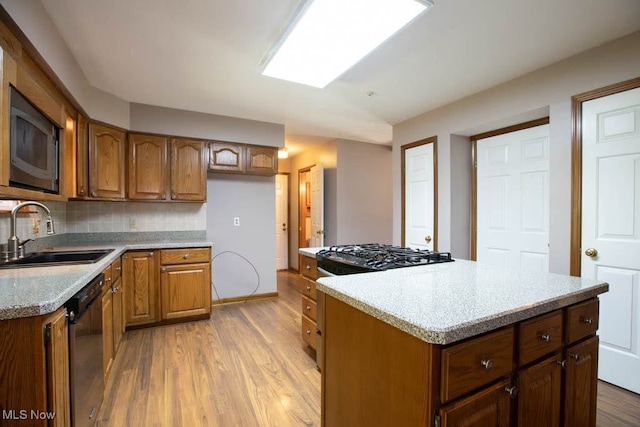 kitchen with sink, light hardwood / wood-style flooring, backsplash, appliances with stainless steel finishes, and a center island