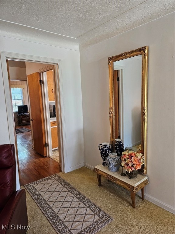 corridor with a textured ceiling and hardwood / wood-style floors