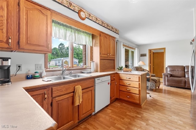 kitchen featuring light wood-type flooring, plenty of natural light, white dishwasher, and sink