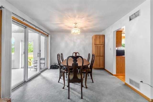 dining space featuring light colored carpet and a notable chandelier