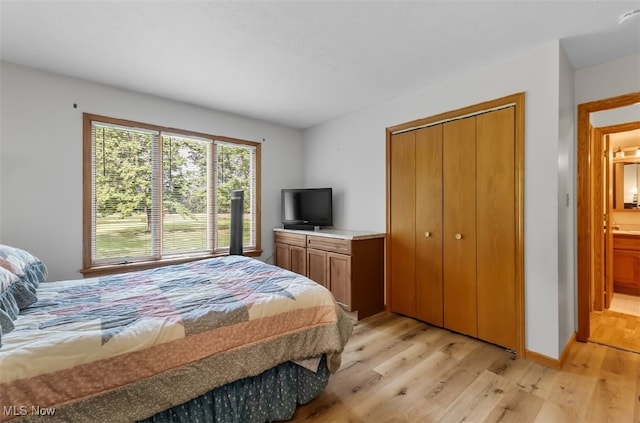 bedroom with light hardwood / wood-style flooring, ensuite bath, and a closet