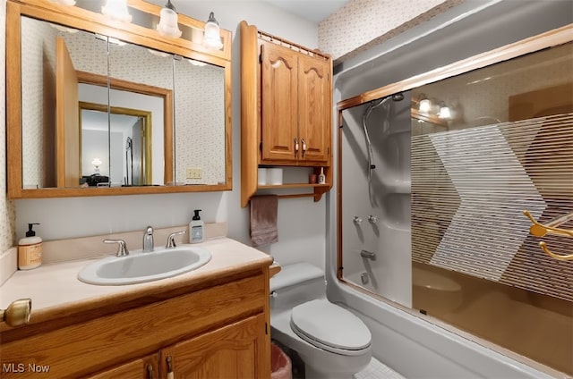 full bathroom featuring toilet, bath / shower combo with glass door, and vanity