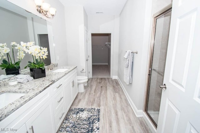 bathroom with an inviting chandelier, hardwood / wood-style floors, toilet, a shower with door, and vanity