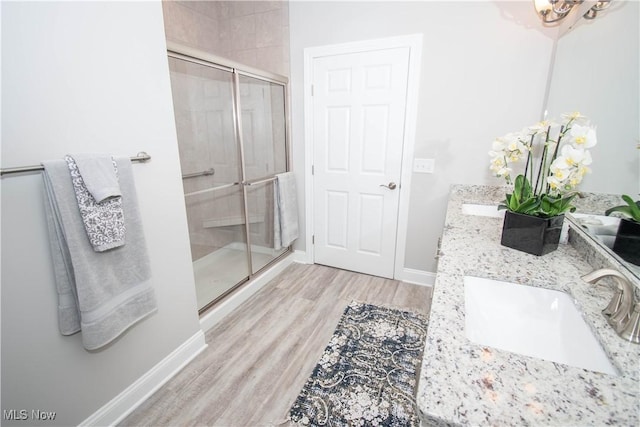 bathroom with hardwood / wood-style floors, vanity, and a shower with shower door