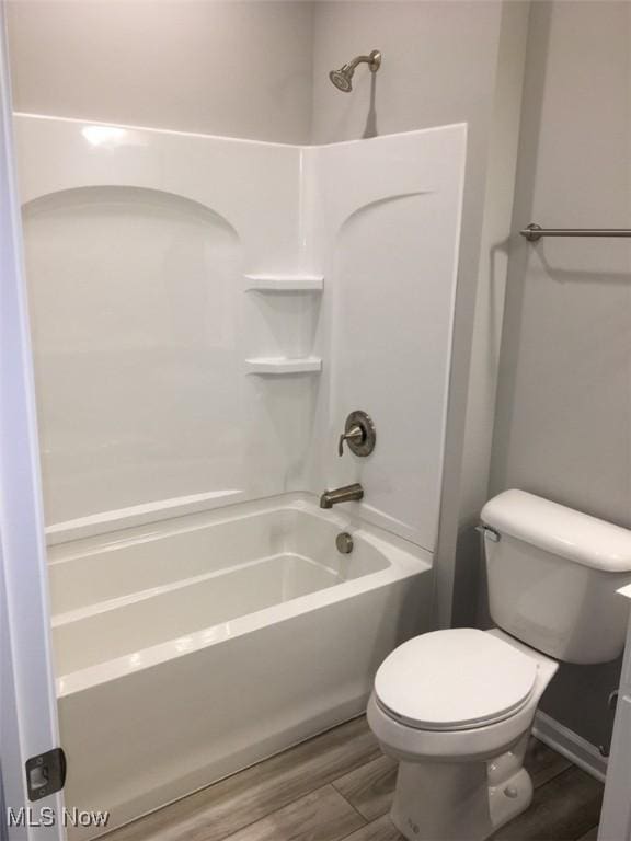 bathroom with toilet, wood-type flooring, and tub / shower combination