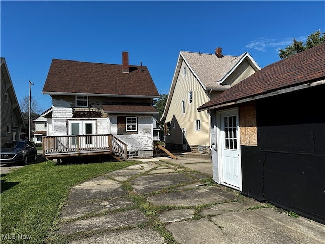 back of property with a lawn and a deck