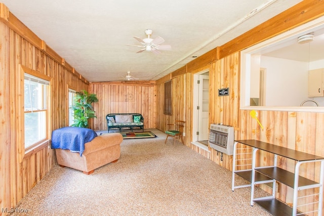 unfurnished living room featuring ceiling fan, wooden walls, carpet, and heating unit