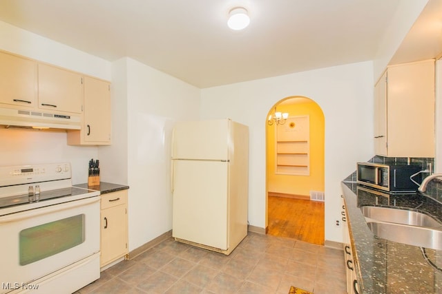 kitchen with light wood-type flooring, cream cabinetry, white appliances, an inviting chandelier, and sink