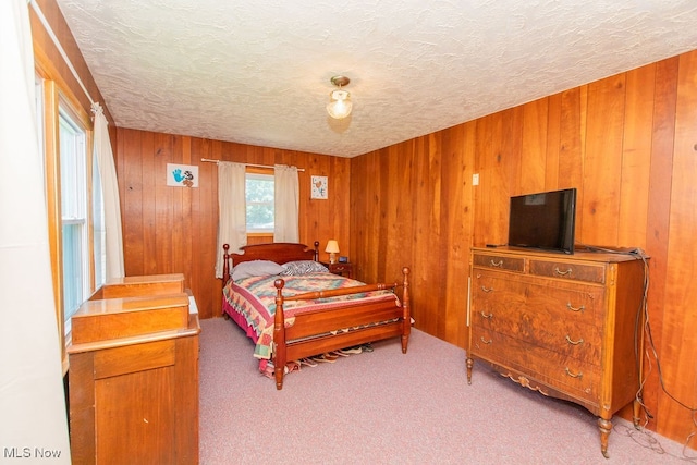 bedroom featuring wood walls, light colored carpet, and a textured ceiling