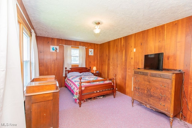 carpeted bedroom with a textured ceiling and wooden walls