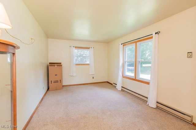 carpeted spare room featuring a baseboard heating unit and plenty of natural light