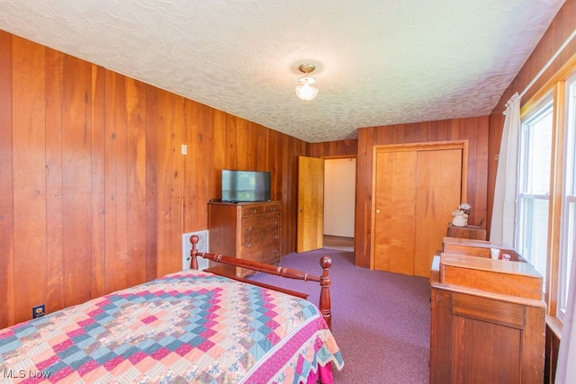 bedroom featuring a closet, a textured ceiling, wooden walls, and carpet