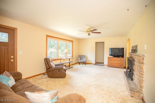 living room with light colored carpet, ceiling fan, and a stone fireplace