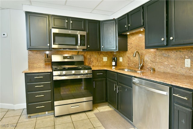 kitchen featuring light stone counters, stainless steel appliances, light tile patterned floors, and sink