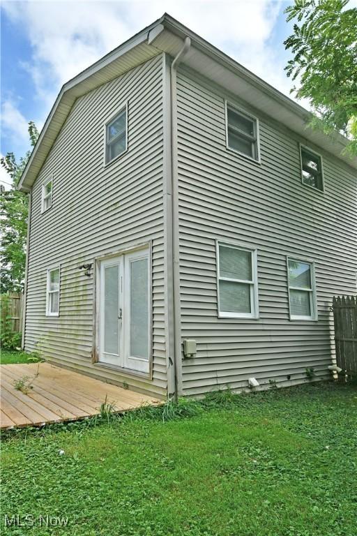 rear view of property featuring a lawn and a deck