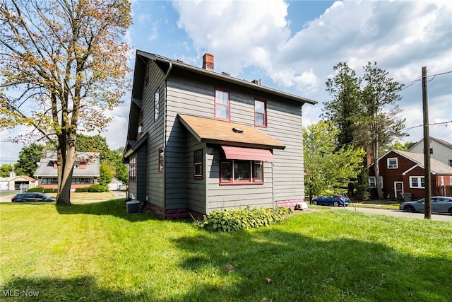 rear view of house featuring central AC and a yard