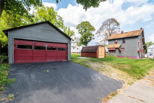 view of front facade featuring a front lawn, a shed, and a garage