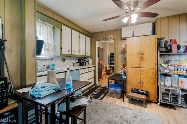 kitchen featuring ceiling fan, light wood-type flooring, white cabinetry, and wooden walls