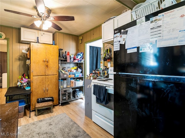 kitchen featuring wooden walls, electric stove, black refrigerator, ceiling fan, and light hardwood / wood-style floors