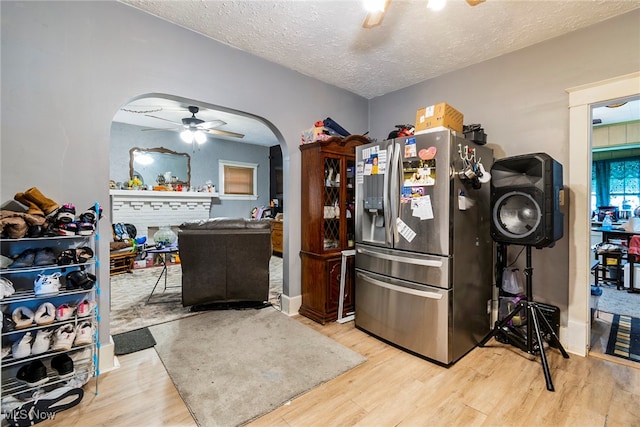 kitchen with a textured ceiling, light hardwood / wood-style flooring, ceiling fan, and stainless steel fridge