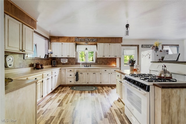 kitchen with light wood-type flooring, white appliances, sink, and decorative backsplash