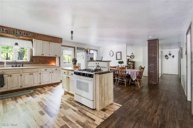 kitchen with hardwood / wood-style floors, white appliances, backsplash, sink, and cream cabinets