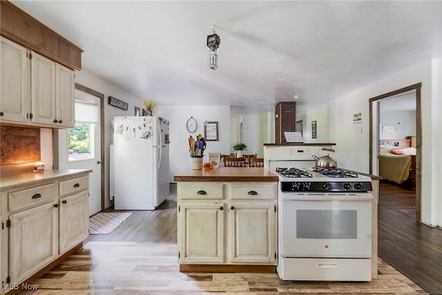 kitchen with cream cabinetry, white appliances, and light hardwood / wood-style flooring