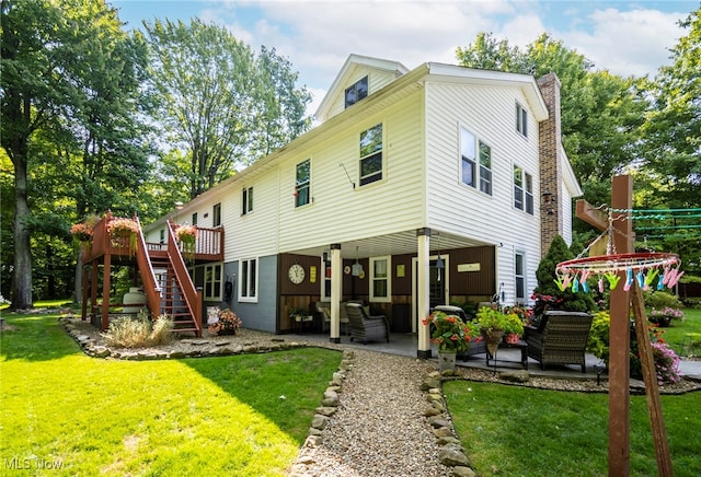 back of house featuring an outdoor living space, a patio area, and a lawn