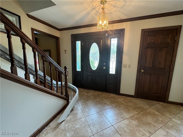 tiled foyer featuring an inviting chandelier, crown molding, and a textured ceiling