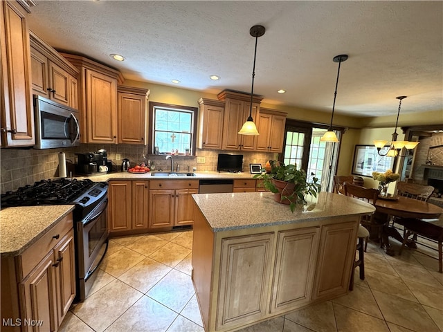 kitchen featuring backsplash, decorative light fixtures, a center island, light stone countertops, and appliances with stainless steel finishes