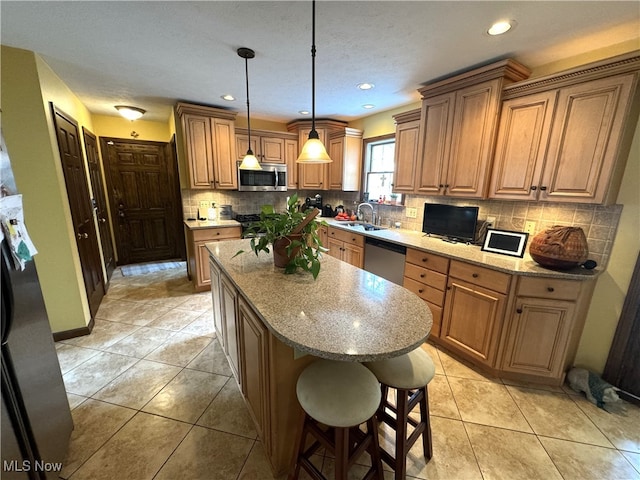 kitchen featuring sink, a kitchen island, stainless steel appliances, and light stone countertops