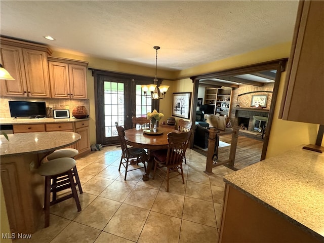 dining area featuring french doors, light tile patterned floors, a chandelier, and a fireplace