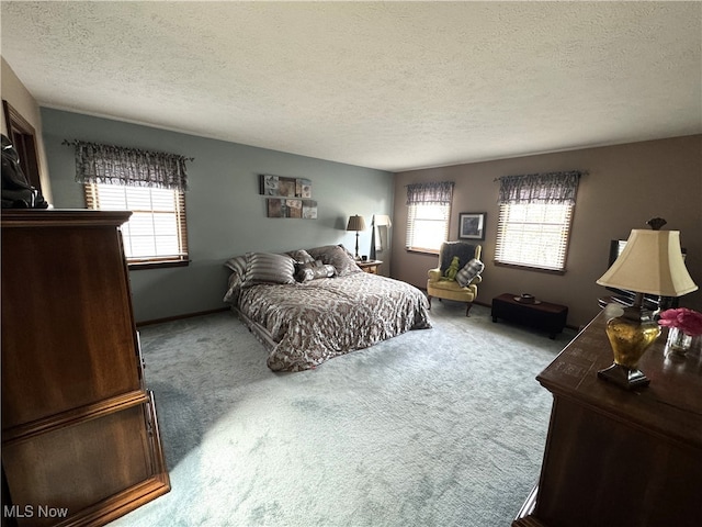 carpeted bedroom featuring a textured ceiling and multiple windows