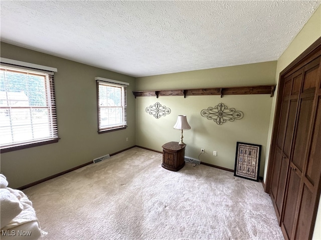 unfurnished bedroom featuring a textured ceiling and light colored carpet