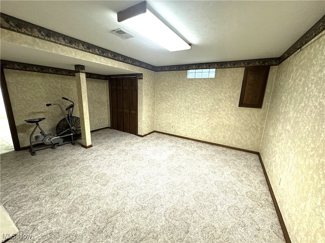 basement featuring light colored carpet and a textured ceiling