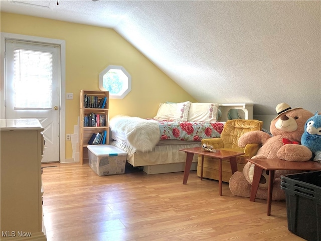 interior space featuring light wood-type flooring, a textured ceiling, and vaulted ceiling