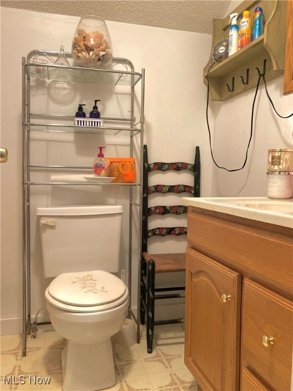 bathroom with a textured ceiling, vanity, and toilet