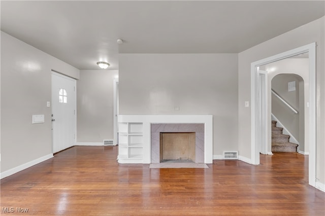 unfurnished living room featuring dark wood-type flooring and a premium fireplace