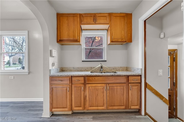 kitchen with dark hardwood / wood-style flooring, light stone counters, and sink