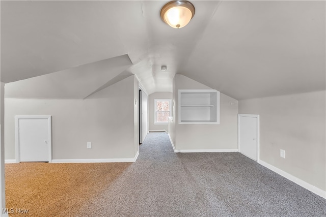 additional living space featuring lofted ceiling, built in shelves, and carpet