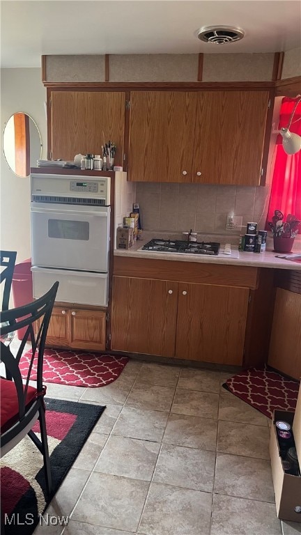 kitchen with backsplash, white oven, and gas cooktop