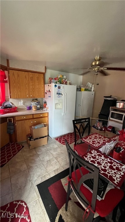 kitchen featuring light tile patterned floors, ceiling fan, white fridge with ice dispenser, and white fridge