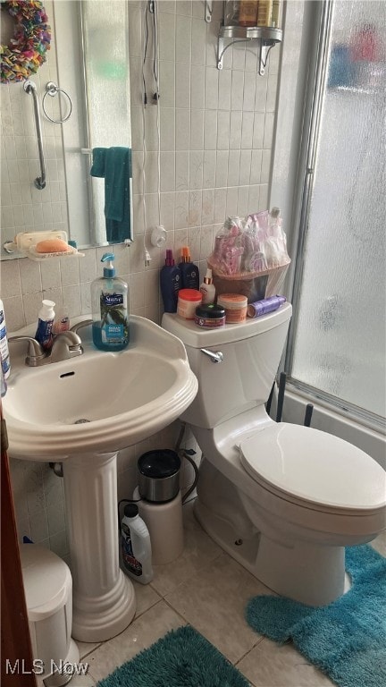 bathroom with an enclosed shower, tile walls, toilet, and tile patterned floors